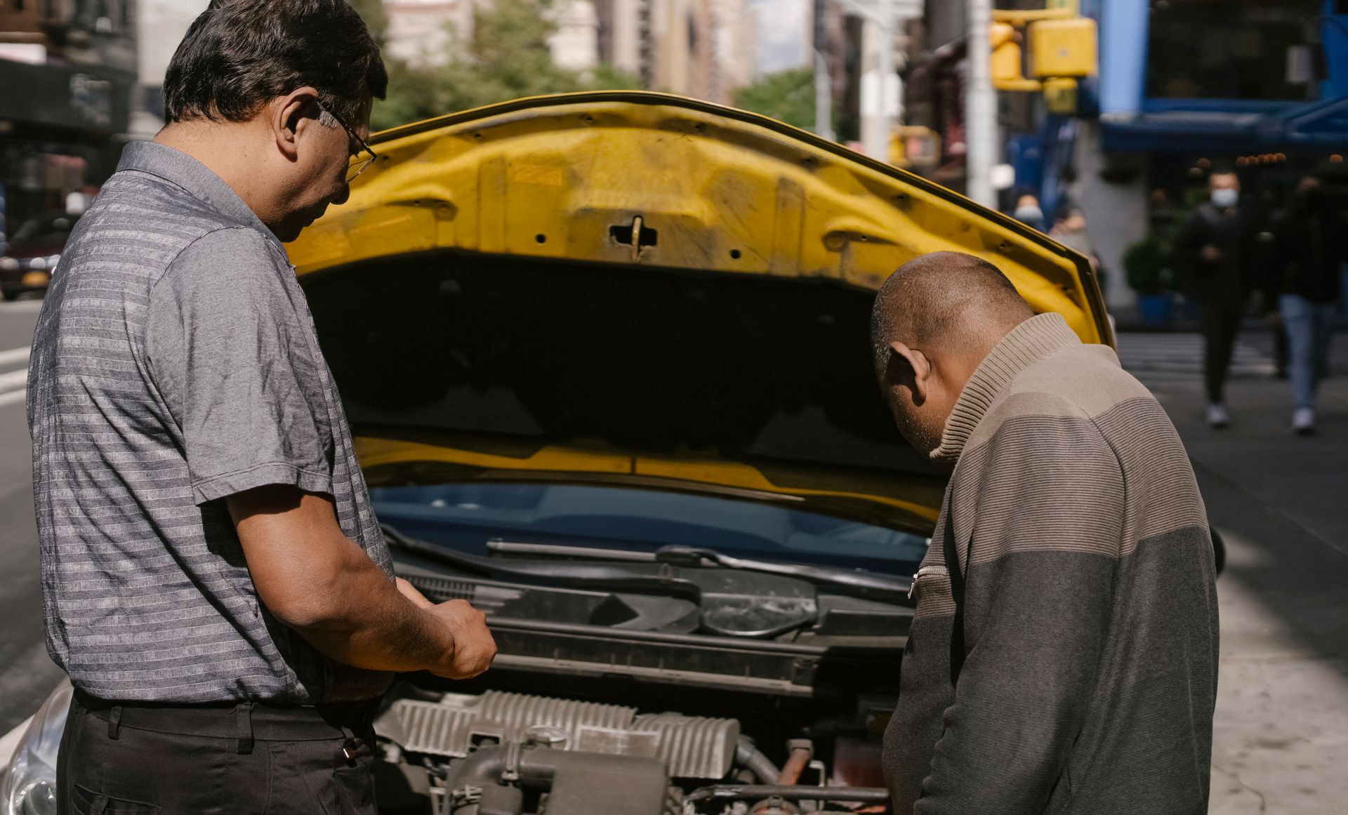 People checking a car with its hood open at the roadside